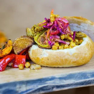 a hot dog with vegetables on a bun