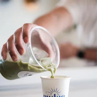 a person pouring a cup of matcha