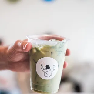 a hand holding a cup of green tea