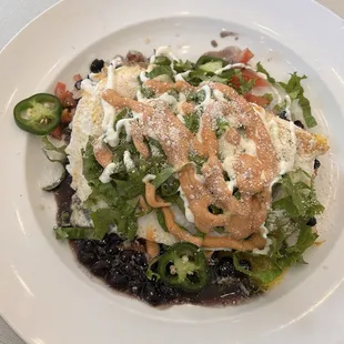 Huevos Rancheros: over easy eggs atop crispy hash browns, black beans, shredded lettuce and jalapeño w/a lime cilantro sour cream drizzle.