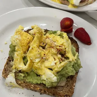 a plate of eggs, avocado and strawberries