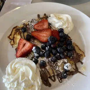 Sweet ricotta filled crepes with berries and Nutella drizzle.