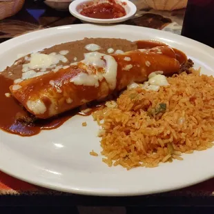 Beef burrito with a side of beans and rice.