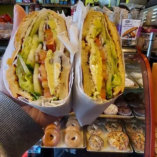 a person holding two sandwiches