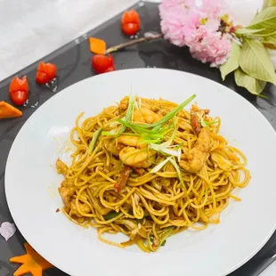 a plate of noodles with shrimp and vegetables