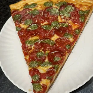 A slice of pesto pepperoni pizza..