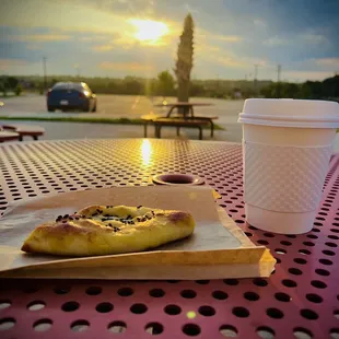 a cup of coffee and a piece of pizza on a table