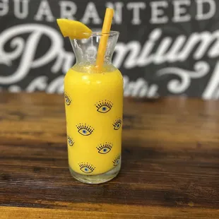 a glass of orange juice with a straw in it