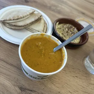 Red lentil soup with a side of pita and hummus