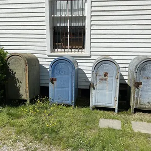 a row of old mail boxes in front of a house
