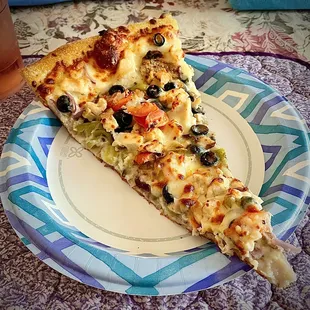 One slice of King Kong size pizza on a dinner-size paper plate.
