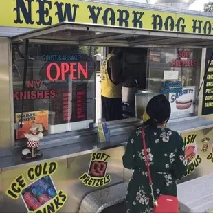 a woman standing in front of a food cart