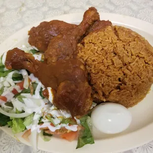 Jollof rice with chicken, salad and an egg.