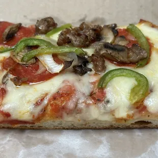 a slice of pizza with pepperoni, mushrooms, and cheese