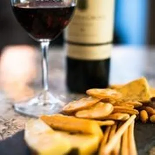 a cheese board with crackers and a glass of wine