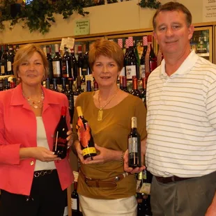 a man and woman holding bottles of wine