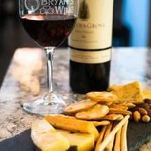 a glass of red wine, cheese and crackers