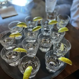 a tray of shot glasses with lemon wedges