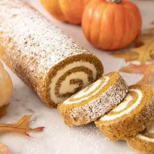 a pumpkin roll with powdered sugar and pumpkins in the background