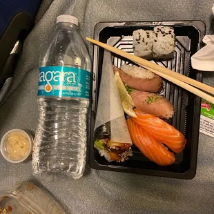 a plastic container with chopsticks and a bottle of water