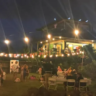 Outdoor stake lighting in the yard along with tables and chairs from Oahu Party Rentals.