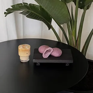 a glass of iced coffee and a pair of pink macarons