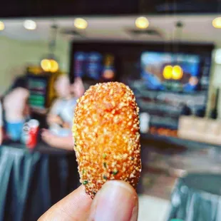 a hand holding a fried fish and chips
