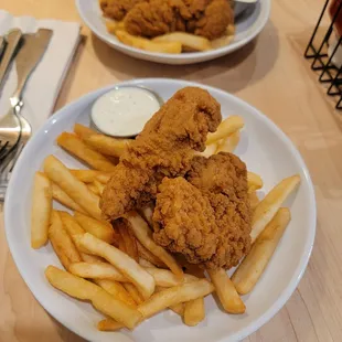 two plates of fried chicken and french fries