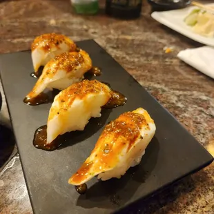 three pieces of sushi on a black plate