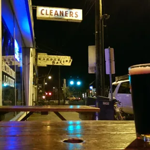 Outside, leaning against the window, on the bench, drinking a cold dark beer late at night when it is dead quiet on the street.