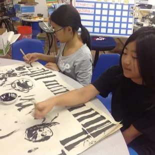Art students working on their Chinese bamboo brush skills. Their art classes have been progressing from one art material to another.