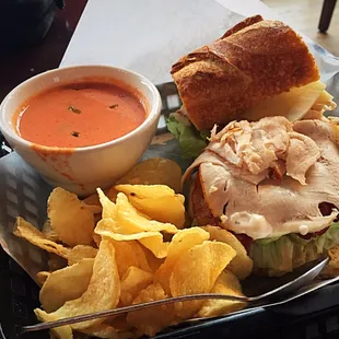 Turkey Bacon Ranch sandwich on a crusty sourdough baguette with crunchy chips and a sup of creamy tomato soup.
