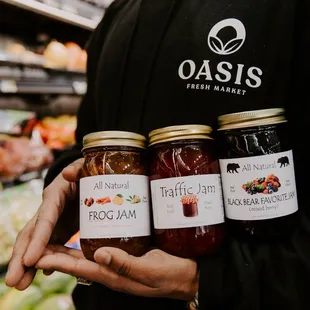 a man holding three jars of jam