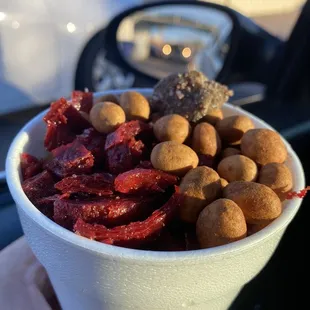 a person holding a cup of fruit cones