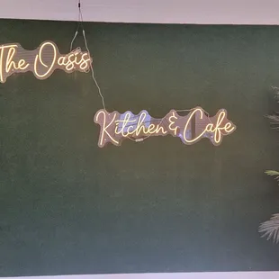 a neon sign for the oasis kitchen and cafe
