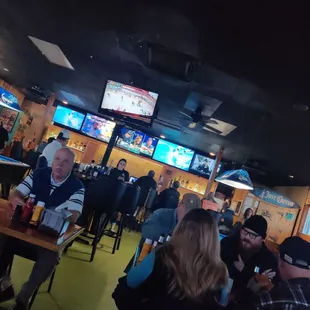 a group of people sitting at tables watching televisions