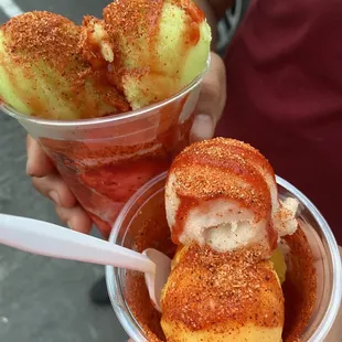 a person holding two cups of ice cream