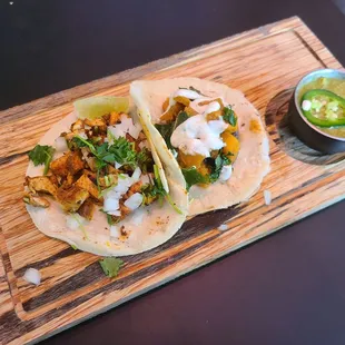 Pollo Asado Taco (tangy achiote-rubbed grilled chicken, cilantro, onion) and Squash, Kale, and Mushroom Taco w/cumin lime crema