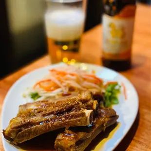 a plate of ribs and vegetables with a glass of beer