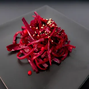 a black plate with a pile of sliced red onions