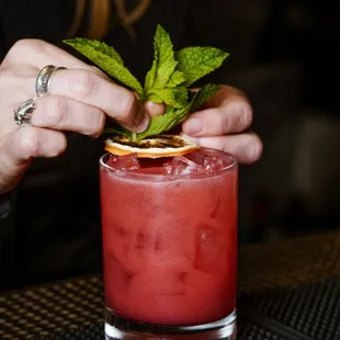 a woman placing a garnish on a cocktail