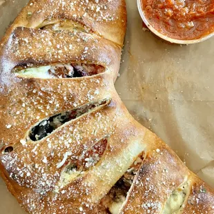 Sicilian Calzone. Stuffed with mozzarella, ricotta, sausage, pepperoni, red onion, mushroom, black olives, and their special sauce.