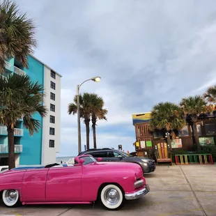 a pink classic car parked in a parking lot