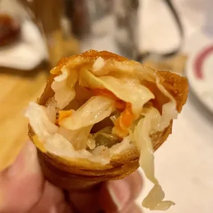 a hand holding a pastry with sauerkraut