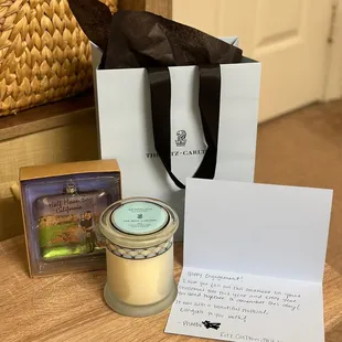 a candle, gift bag, and note on a table