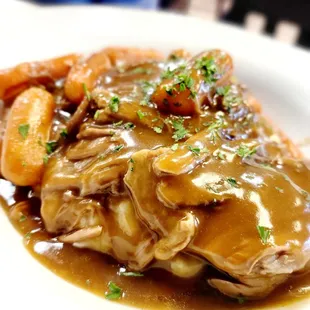 a plate of meat with gravy and carrots