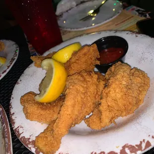 a plate of fried chicken with a side of dipping sauce