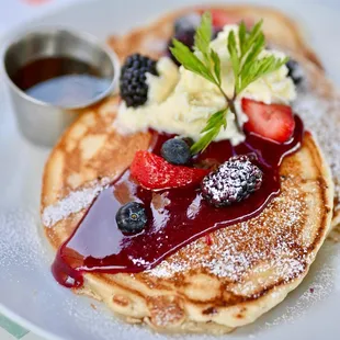 a plate of pancakes with syrup and berries