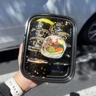 a person holding a tray of sushi