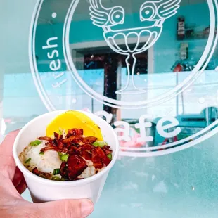 a hand holding a bowl of food